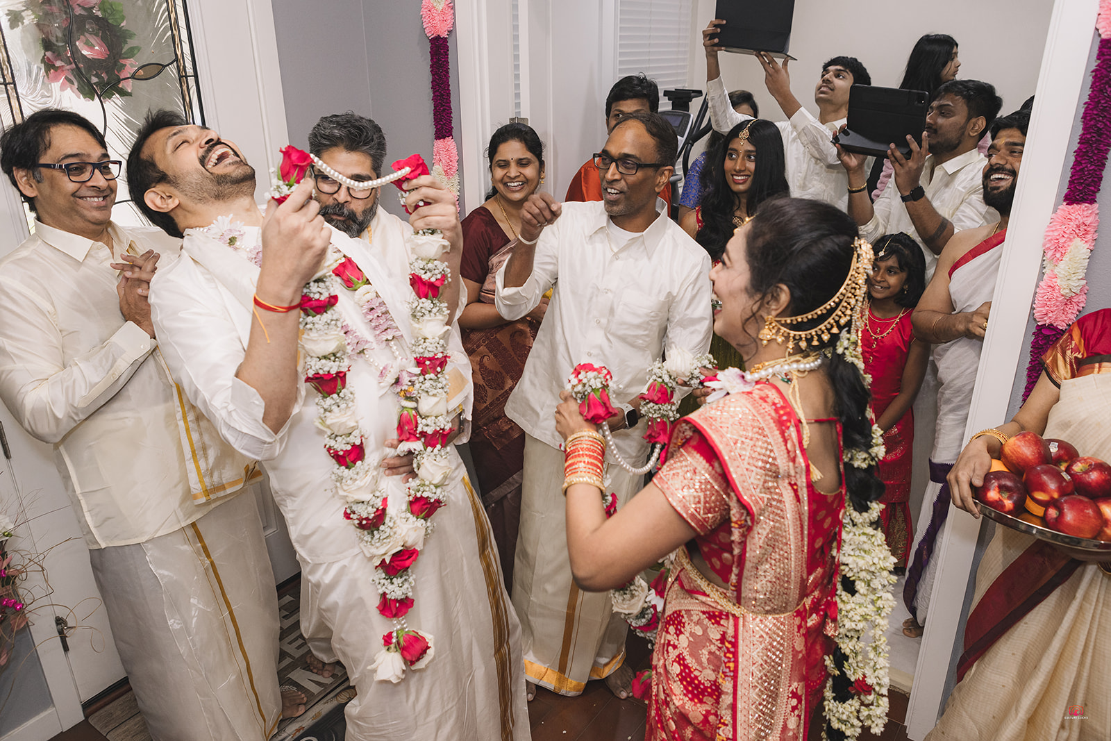 Families celebrating a joyful garland exchange at an Indian wedding
